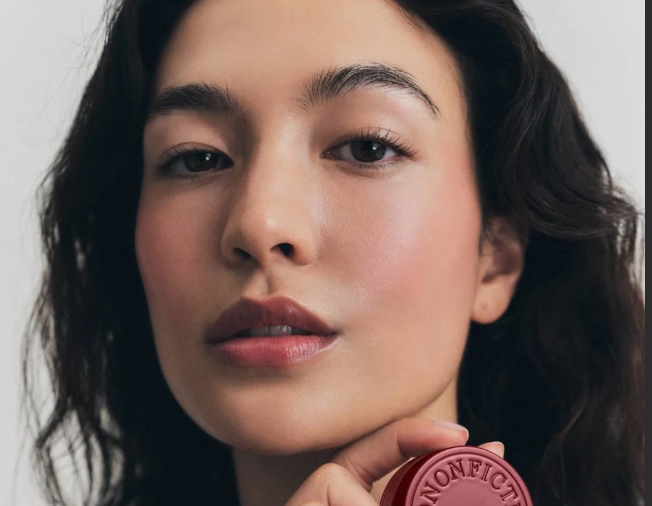 Model holding a burgundy Vintage Rose balm.